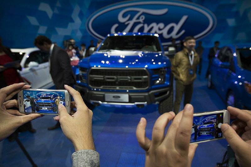 Attendees at the Auto China car show in Beijing in April take photos of a Ford F-150 Raptor pickup. Ford on Thursday reported a quarterly profit of $957 million.