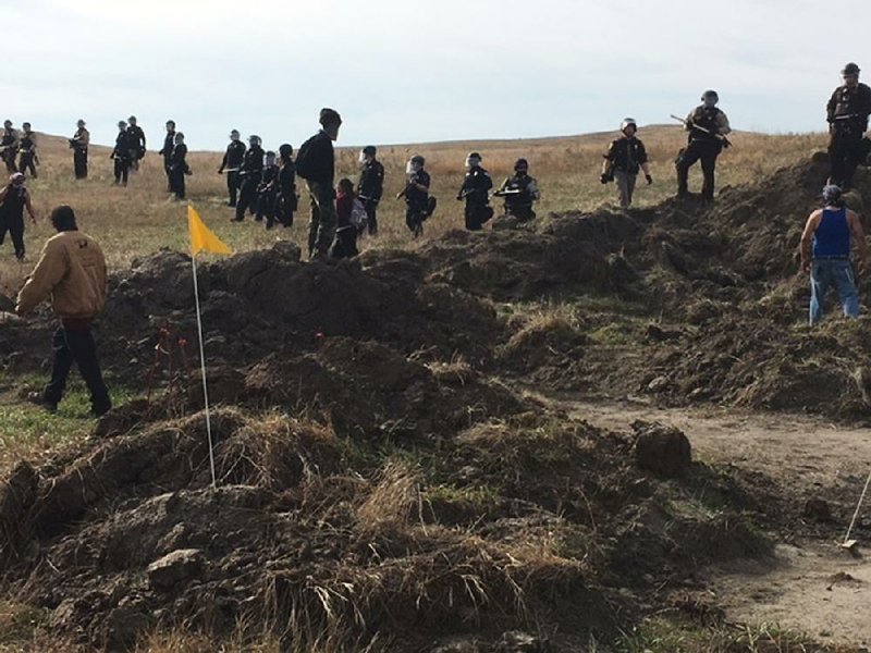 Demonstrators stand by as armed soldiers and law enforcement officers moved in to force Dakota Access pipeline protesters off private land where they had camped to block construction in North Dakota on Thursday. 
