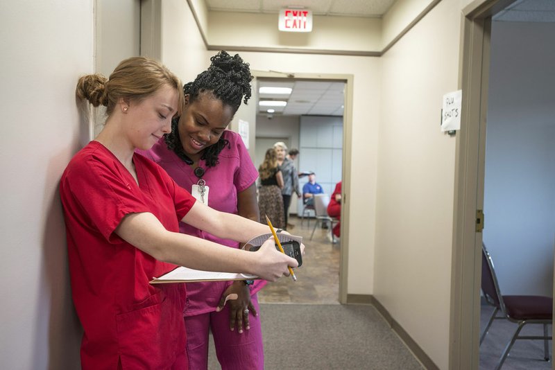 Hannah Scott (left), nursing senior at the University of Arkansas, looks over a statistics sheet Thursday with Quinita Henry, registered nurse with the Washington County Health Department, that kept track of the number and time of patients Henry saw at the county courthouse in Fayetteville. The pair joined other State Health Department workers, emergency personnel from Washington and Benton counties and students with the University of Arkansas in a simulation of a bioterrorism attack.