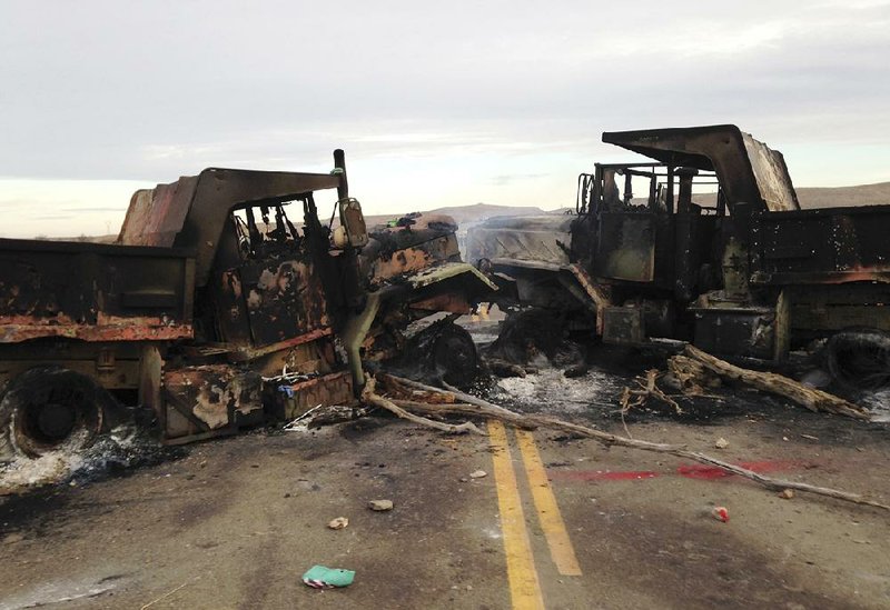 The burned hulks of heavy trucks sit on a highway Friday near Cannon Ball, N.D., near the spot where people protesting the Dakota Access pipeline were evicted from private property.