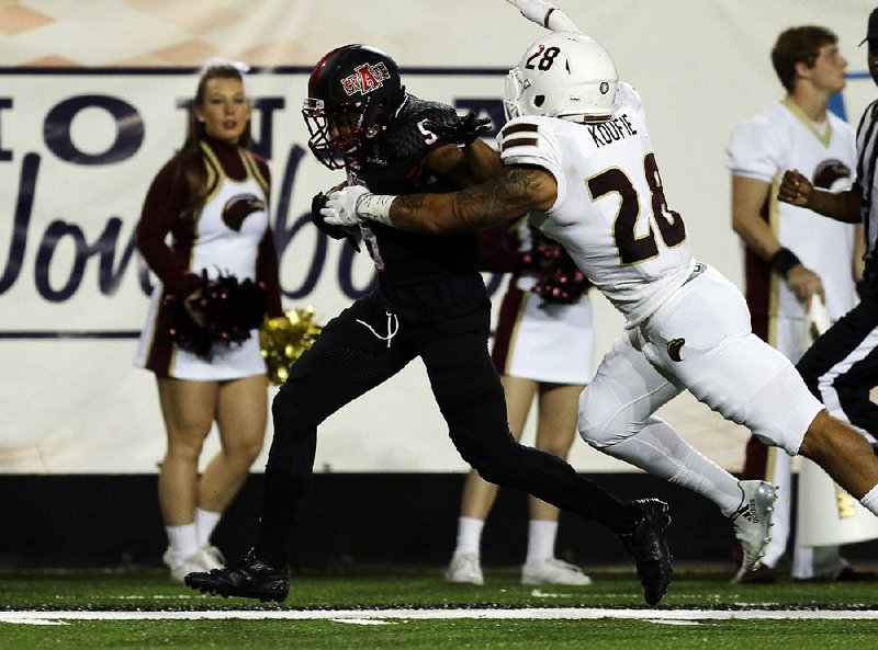 Arkansas State’s Daryl Rollins-Davis (left) runs down the sidelines while trying to shove off Louisiana-Monroe’s Thomas Koufie in Saturday night’s game at Centennial Bank Stadium in Jonesboro. The Red Wolves won 51-10 to move to 3-0 in the Sun Belt Conference.