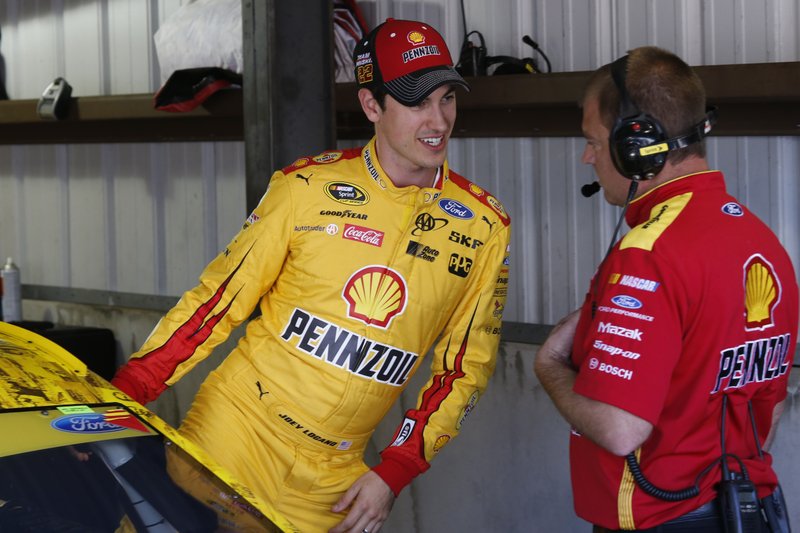 Driver Joey Logano, left, talks to a crew member as he prepares for practice for Sunday's NASCAR Sprint Cup auto race at Martinsville Speedway in Martinsville, Va., Saturday, Oct. 29, 2016. 