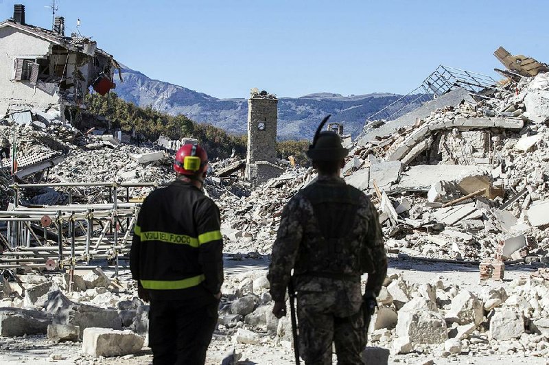 A firefighter (left) and an alpine soldier look at rubble in the hilltop town of Amatrice after an earthquake with a preliminary magnitude of 6.6 struck central Italy on Sunday.