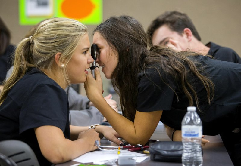 Mallory Keith (left) and Molly Miller, both Bentonville High juniors, perform physical examinations Wednesday at the Center for Health Professions Building at Northwest Arkansas Community College in Bentonville. The students are part of the Ignite Medical & Health Sciences class.