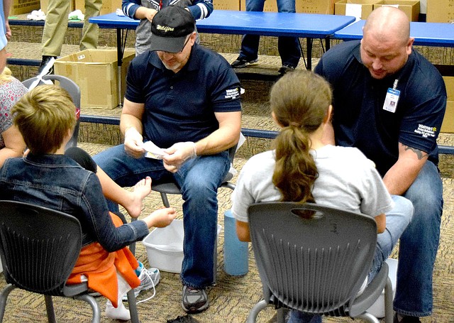 Photo by Mike Eckels Two volunteers from Walmart Distribution Center 6051 in Bentonville talked to a pair of students during the Samaritan&#8217;s Feet distribution at Decatur Northside Elementary School Oct. 28. Walmart DC 6051 and Samaritan&#8217;s Feet donated a new pair of socks and shoes to each student at the school.