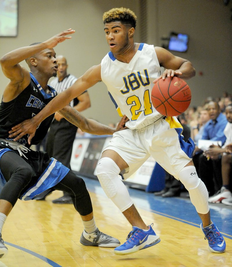 Andy Shupe/NWA Democrat-Gazette Brandon Joseph, No. 24, of John Brown University looks to drive around Jayln McBride of Central Baptist College Saturday at Bill George Arena on the JBU campus in Siloam Springs. Joseph scored 19 points in the Golden Eagles&#8217; 104-94 victory.