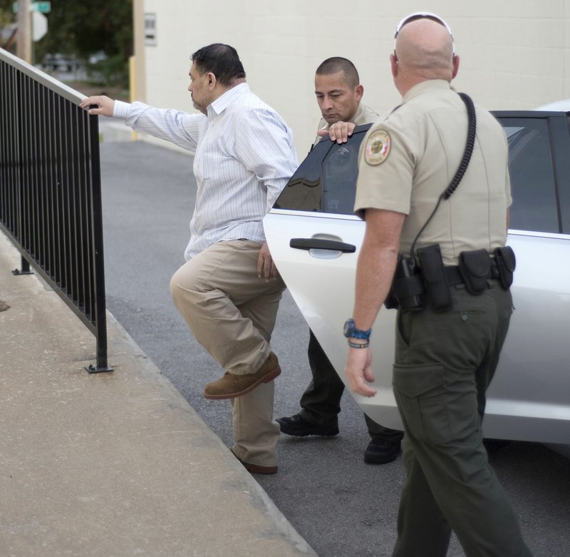 Mauricio Torres of Bella Vista (from left) is escorted Tuesday into the Benton County Courthouse by Deputies Luis Lara and Steve Shipman.