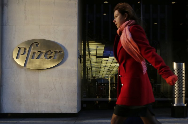 In this Monday, Nov. 23, 2015, file photo, a woman passes Pfizer's world headquarters, in New York. 