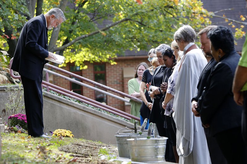 The Rev. Lowell Grisham, rector of St. Paul's Episcopal Church, prays Tuesday over the burial sites of cremains from 14 individuals during the dedication of the St. Joseph of Arimathea Community Memorial Garden at the Fayetteville church. The 14, whose remains had been unclaimed by family or friends, were buried at the site with the permission of the Washington County Coroner Roger Morris.