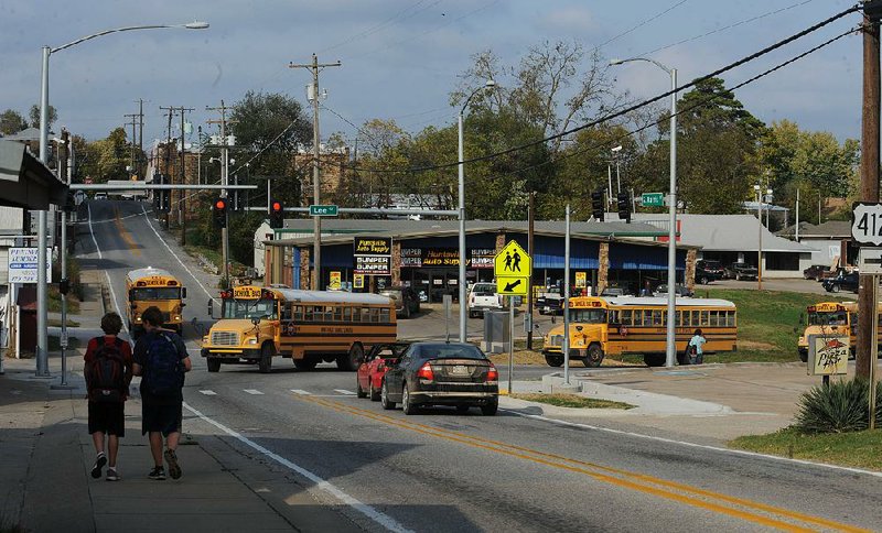 Traffic and pedestrians move Thursday through a newly installed traffic light at Harris and Lee streets in Huntsville at the end of the school day. The light is the first of its kind in Madison County, leaving four other counties in the state without a traffic signal.