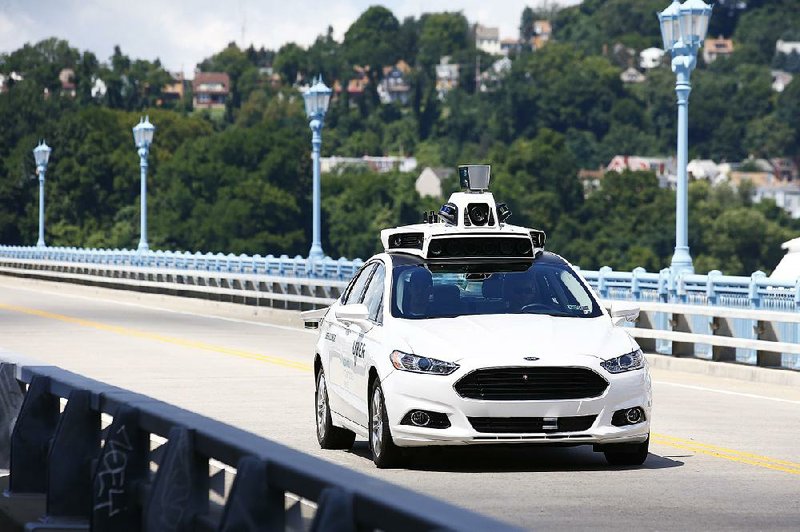 Uber employees test a self-driving Ford Fusion hybrid car in Pittsburgh in August.
