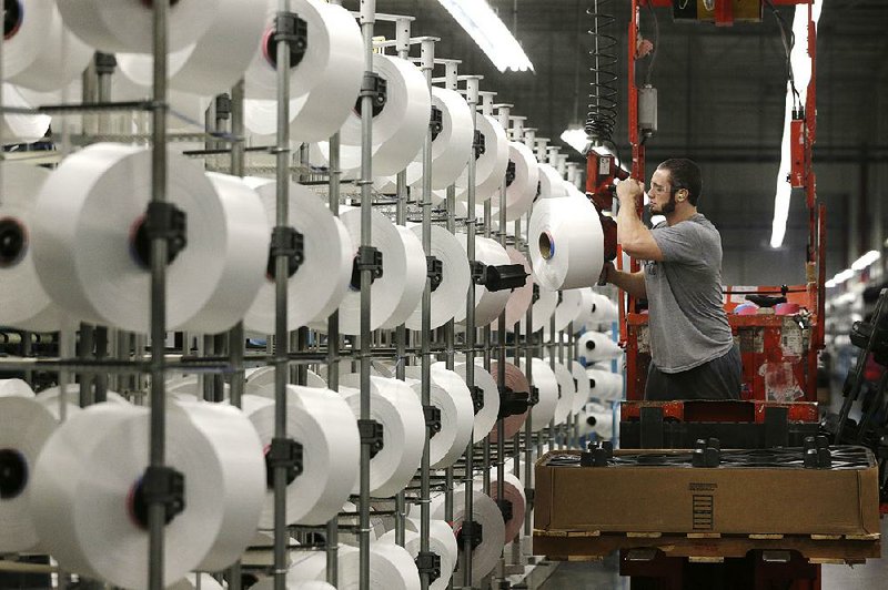 A worker loads spools of thread at the automated Repreve yarn-making plant in Yadkinville, N.C., which is part of the Unifi textile company. Drone carts at the plant now do jobs that people once did.
