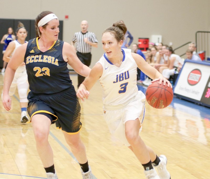 Photo courtesy of JBU Sports Information John Brown University junior guard Jana Schammel drives past Ecclesia&#8217;s Mikayla Roberts, a former Greenwood standout, during Monday&#8217;s game at Bill George Arena. Schammel scored 11 points in the Golden Eagles&#8217; 110-37 win.