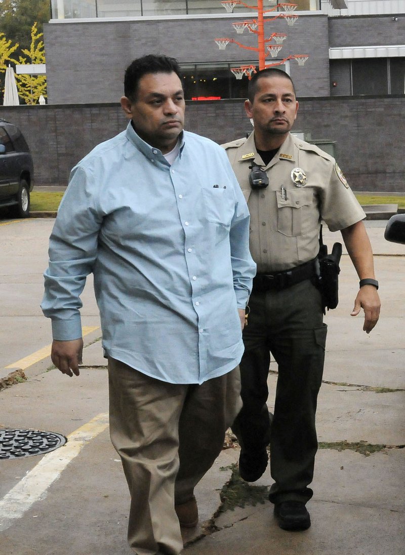 Mauricio Torres (left) is escorted Tuesday into the Benton County Courthouse annex in Bentonville.