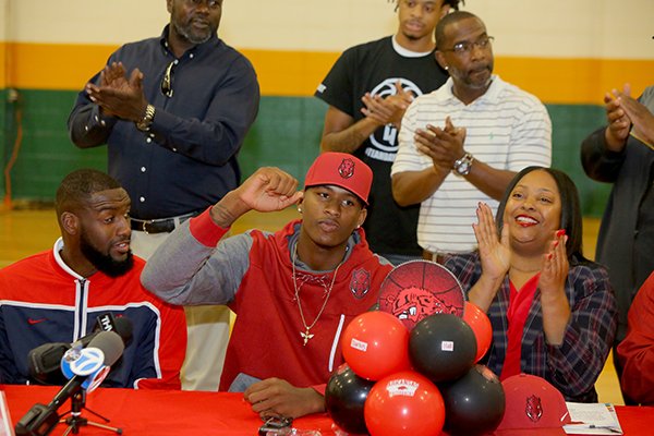 Mills basketball player Darious Hall, center, celebrates with a coach Raymond Shaw, left, and his mother Alice Plant, right, and other family and friends during his UA signing ceremony Wednesday, Nov. 9, 2016, in Little Rock.