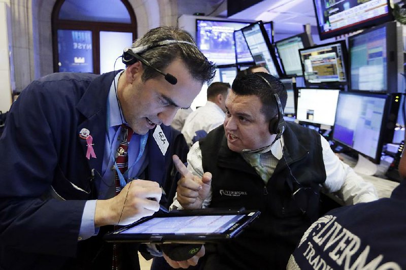 Traders Gregory Rowe (left) and Robert Finnerty work in a booth on the floor of the New York Stock Exchange during brisk activity Wednesday.