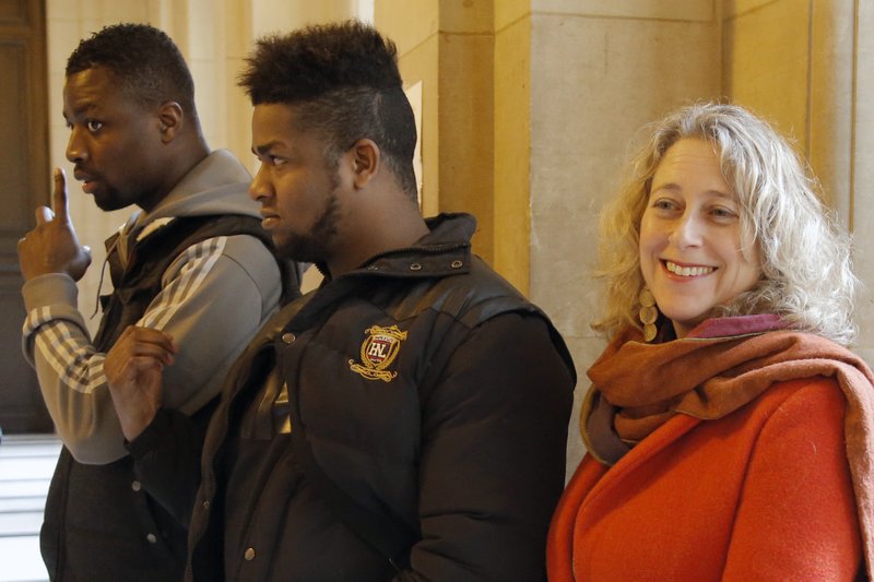 In this Feb. 25 2015 file photo, French plaintiffs Regis Amponsah, left, and Elize Novembre, right, stand with Lanna Hollo, senior legal officer with Open Society Justice Initiative, and talk to the media at Paris appeals court, in Paris. 