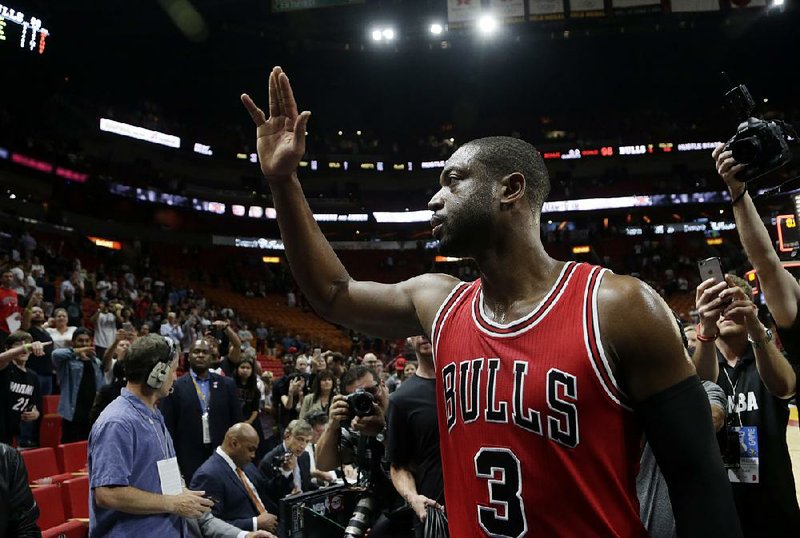Chicago guard Dwyane Wade waves to the crowd Wednesday after scoring 13 points to lead the Bulls to a 98-95 victory over the Miami Heat. It was Wade’s fi rst game in Miami since signing with Chicago as a free agent in the offseason.