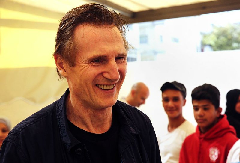 In this Tuesday, Nov. 8, 2016 photo, actor Liam Neeson, listens to stories from Syrian and Jordanian students, at a community center in a working-class neighborhood of Amman, Jordan. 