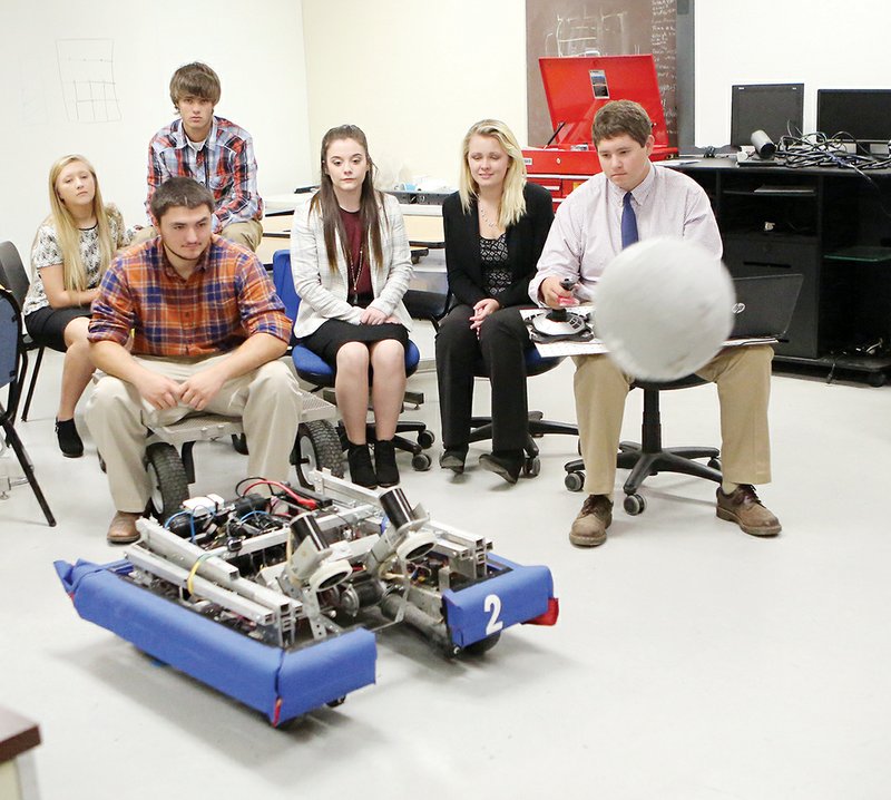 Members of the Cedar Ridge High School robotics team include, front row from left, Greg Fitzgerald, Kailseigh Barnes, Katlyn Reilly and Jake Butler; and back row, Lindsay Hackworth and Aaron Merrill. Butler demonstrates how the team’s robot catapults a ball. The students built the robot for last year’s competition.