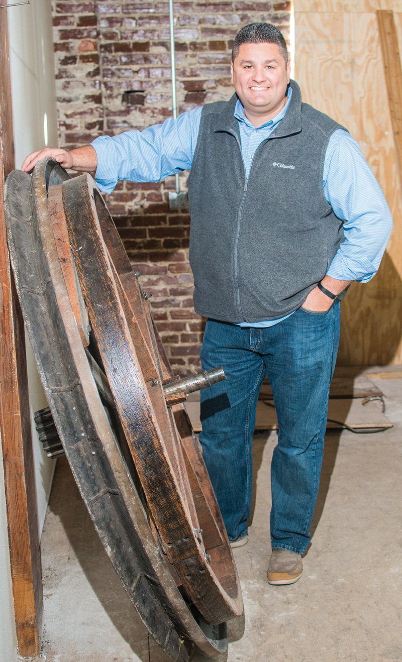 Mat Faulkner stands by the large gear that was used for the freight elevator in the historic Robbins Sanford mercantile building in downtown Searcy that Faulkner and his wife, Shelley, are renovating.