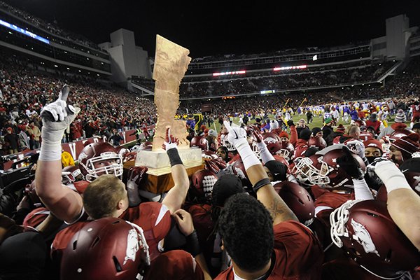 Arkansas players celebrate with The Boot trophy following a 17-0 win over LSU on Saturday, Nov. 15, 2014, in Fayetteville. 