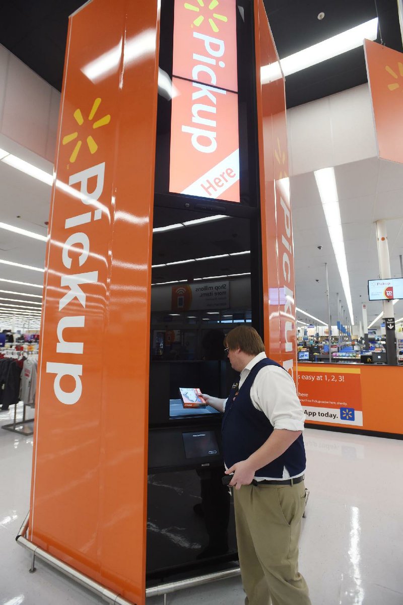 Justin Wright, department manager for pickup at a Wal-Mart Supercenter in Rogers, demonstrates how a 16-foot tower distribution system works. The dispensing device is being tested at the Northwest Arkansas store. 
