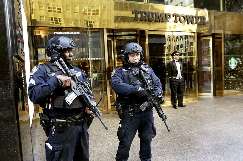 New York police officers stand guard with assault rifl es Friday in front of Trump Tower. Security measures around the Fifth Avenue landmark have turned the skyscraper into a fortress.