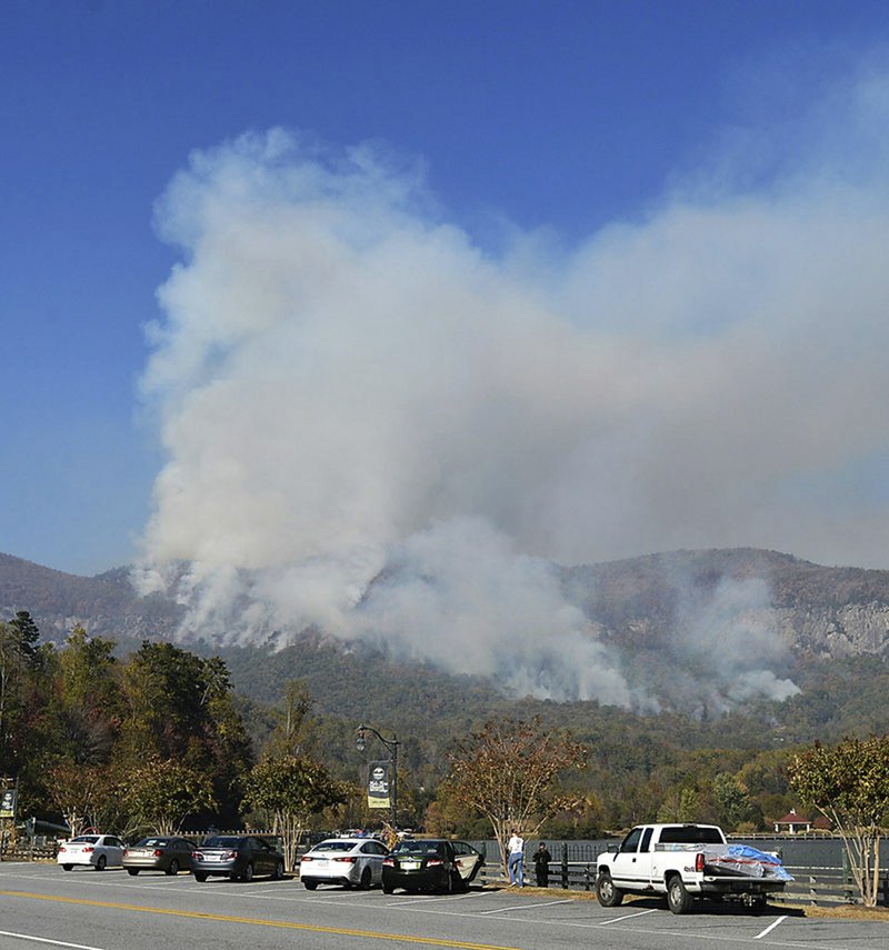 People take photos of a wildfire burning near Lake Lure, N.C., Thursday, Nov. 10, 2016. A state of emergency is in effect for 25 western North Carolina counties where active wildfires are burning, caused by the drought that began last spring. Gov. Pat McCrory said in a news release Thursday that he was declaring the state of emergency for one-quarter of North Carolina's 100 counties. 