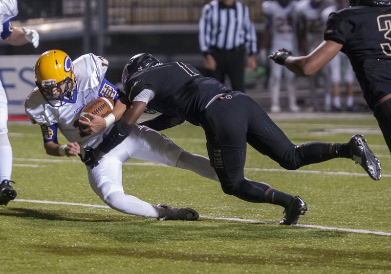 Little Rock Catholic quarterback Taylor Price (left) is tackled by Bentonville’s Tyrell Lyons during Friday night’s Class 7A playoff game at Bentonville. Price was injured on the play and did not return. 