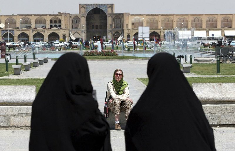 A tourist visiting in 2006 takes in the scene in Isfahan, about 240 miles south of Tehran, as women wearing full-body chadors pass by. Iranian leaders are now trying to open the country to more tourists from the West.