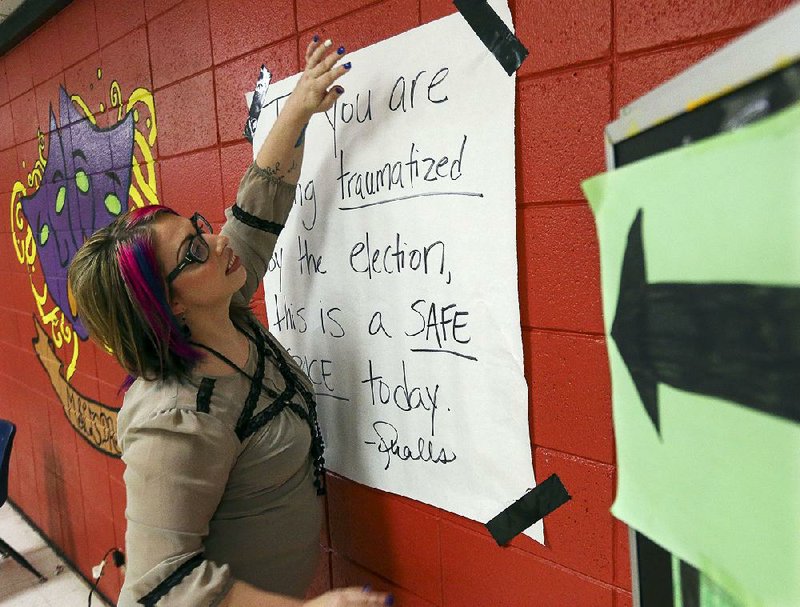 Micah Qualls, a teacher at Mills High School in Little Rock, hangs a sign designating her classroom as a safe space for students to discuss their concerns about Tuesday night’s election results. 