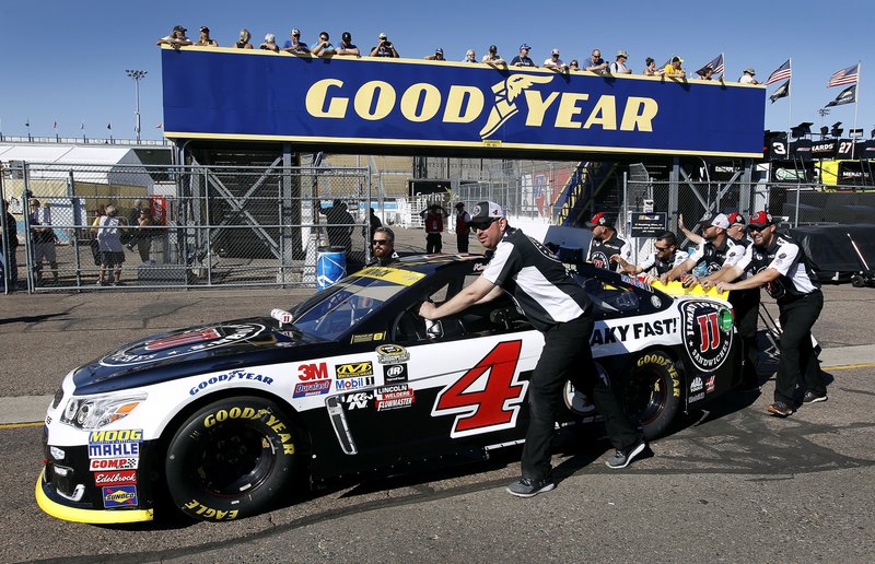 Crew members for driver Kevin Harvick push his car through the garage area before qualifying for the NASCAR Sprint Cup Series auto race at Phoenix International Raceway, Friday, Nov. 11, 2016, in Avondale, Ariz. 