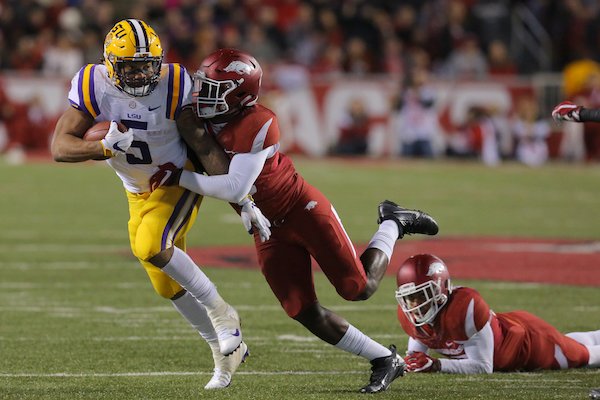 LSU's Derrius Guice (5) breaks away from Arkansas defenders De'Andre Coley, center, and Jared Collins, right, in the third quarter during their game Saturday November 12, 2016 in Fayetteville, Ark.