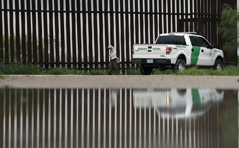 A U.S. Customs and Border Protection agent passes a bird-watcher Sunday along a section of the border wall in Hidalgo, Texas. The value of the peso rose after an adviser to Donald Trump sought to soften the president-elect’s stance on trade with Mexico.