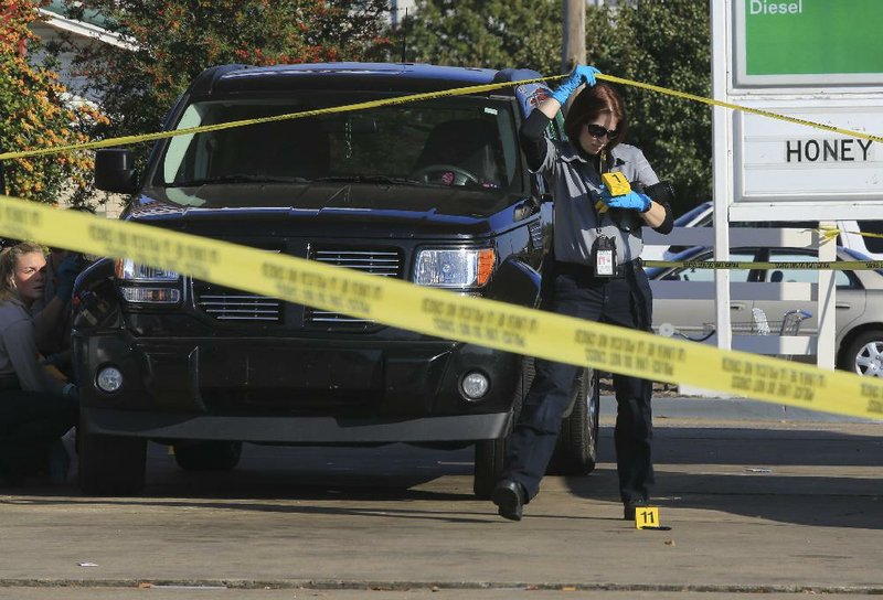 Investigators collect evidence Monday afternoon at the scene of a shooting at the Exxon station at the corner of North Shackleford Road and West Markham Street in Little Rock.