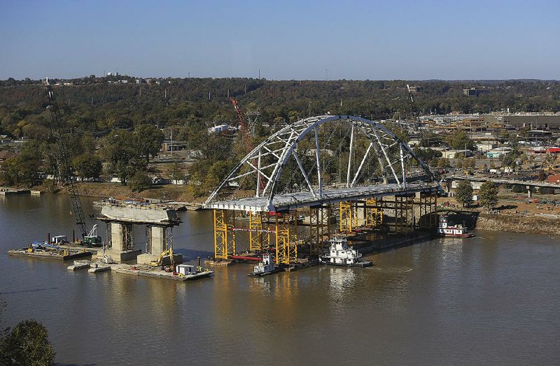 Three towboats nudge the first of two arches for the new Broadway Bridge into place on the Arkansas River in this Nov. 15, 2016 photo.