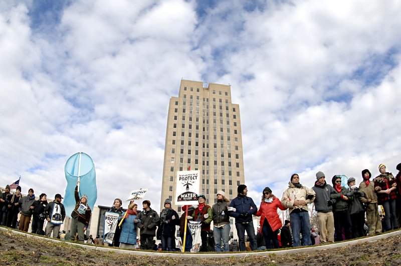 Dakota Pipeline protesters stand arm-in-arm in front of the state Capitol in Bismarck, N.D., before marching downtown to the William L. Guy Federal Building, Monday, Nov. 14, 2016. 