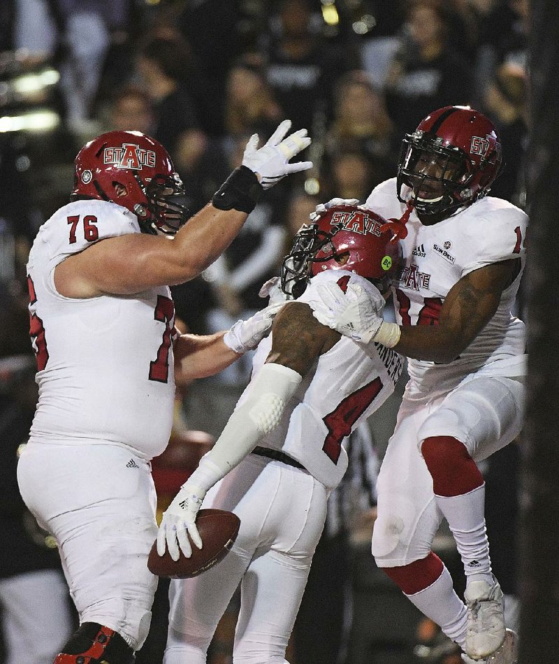 Arkansas State’s Austin Moreton (left) celebrates with Kendall Sanders (center) and Chris Murray after Sanders’ touchdown catch in the first half of Thursday’s game at Veterans Memorial Stadium in Troy, Ala. The Red Wolves took over sole possession of fi rst place in the Sun Belt Conference with a 35-3 victory.