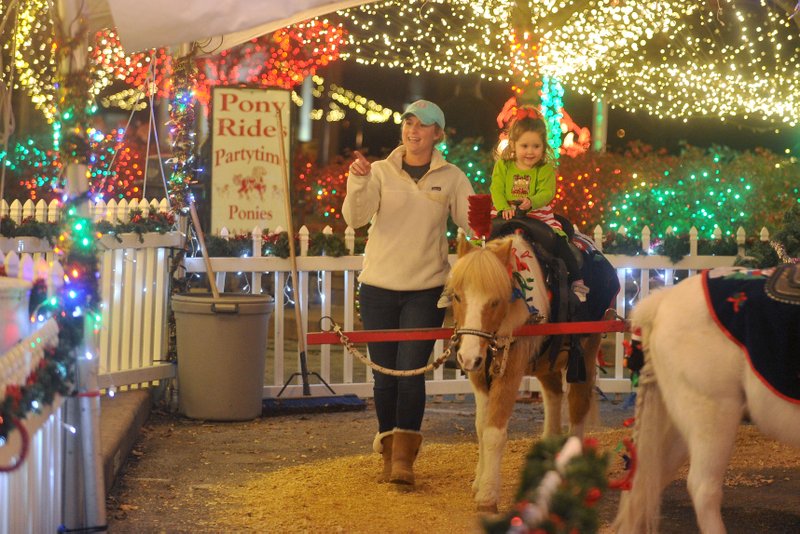 Lauren Lowe walks with her daughter Riley as she rides the Partytime Ponies on the Fayetteville square.