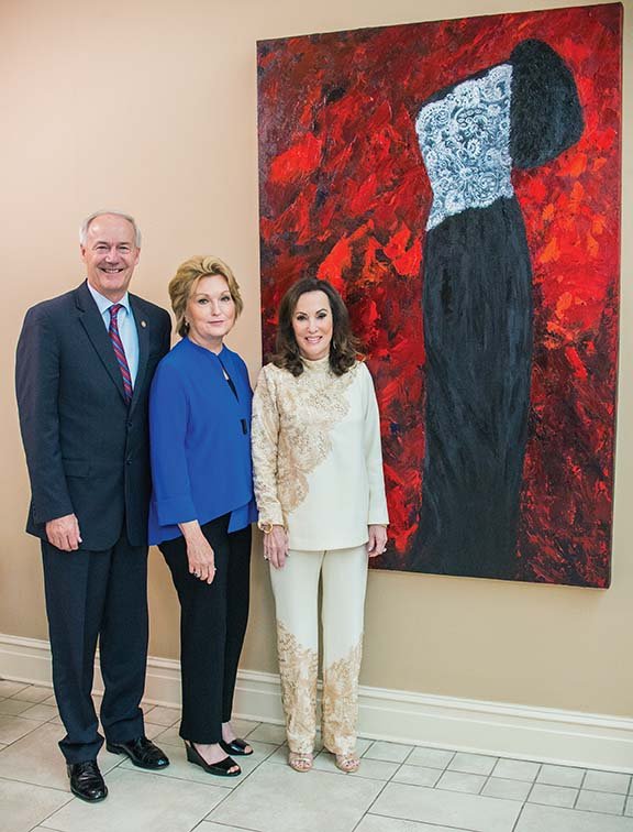 Helen Benton of Heber Springs, right, an artist and dress designer, was honored recently as an Artist in 
Residence at the Arkansas Governor’s Mansion in Little Rock. She is shown here with Gov. Asa Hutchinson and Susan Hutchinson in front of the painting Benton did depicting the gown Susan wore at the Governor’s Inaugural Ball in January 2015. Benton titled the painting Our First Lady: Let her deeds publicly declare her praise. Proverbs 31:31.
