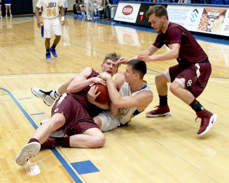 Photo courtesy of JBU Sports Information John Brown sophomore Josh Bowling fights for the ball with a pair of College of the Ozarks (Mo.) defenders during the Golden Eagles&#8217; 71-59 win on Thursday at Bill George Arena.