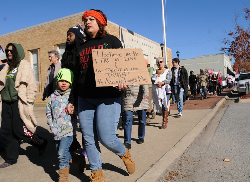 Marchers make their way Saturday through downtown Springdale. Marchers departed about noon from the square, heading west on Emma Avenue. Shouts for equality bellowed from the throng, which also displayed signs advocating for peace and praising diversity.
