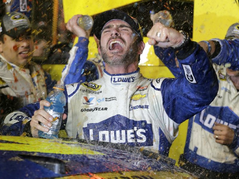 Jimmie Johnson climbs from his car after winning Sunday’s Ford Ecotech 400 at Homestead-Miami Speedway, which gave him a seventh NASCAR Sprint Cup title, tying the series record held by Richard Petty and Dale Earnhardt.