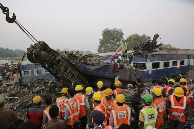 Rescuers search among the debris Sunday after 14 coaches of an overnight passenger train rolled off the track near Pukhrayan village in Uttar Pradesh state, India.
