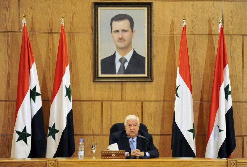 Syrian Foreign Minister Walid al-Moallem sits beneath a portrait of Syrian President Bashar Assad during a news conference Sunday in Damascus, Syria.
