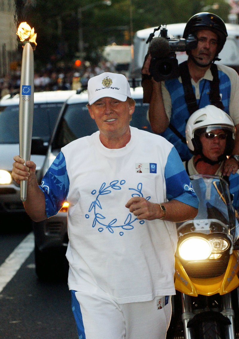 In this Saturday, June 19, 2004 file photo, Donald Trump carries the Olympic Flame on New York's Fifth Avenue during day 15 of the 2004 Athens Torch Relay.