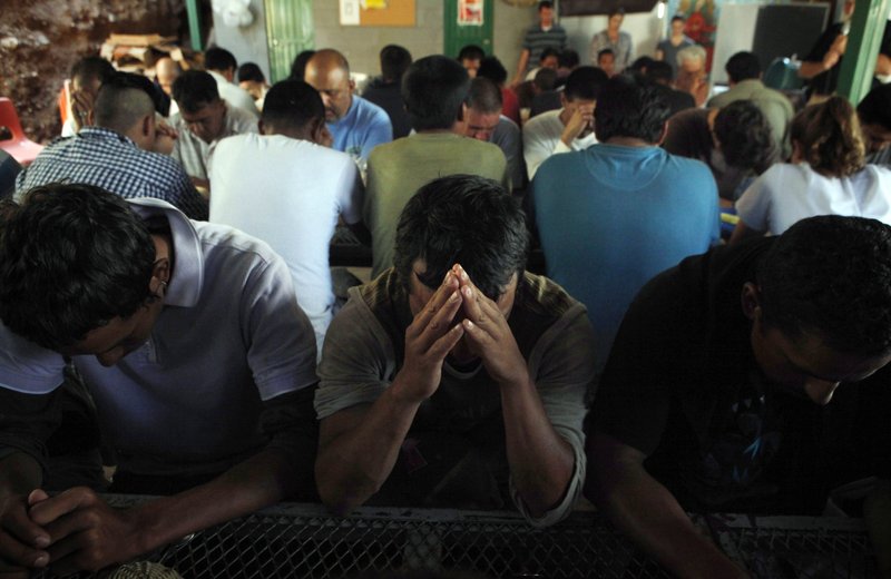 In this July 29, 2010 file photo, deportees pray as they gather for breakfast provided by the Kino Border Initiative in Nogales, Sonora, Mexico. 