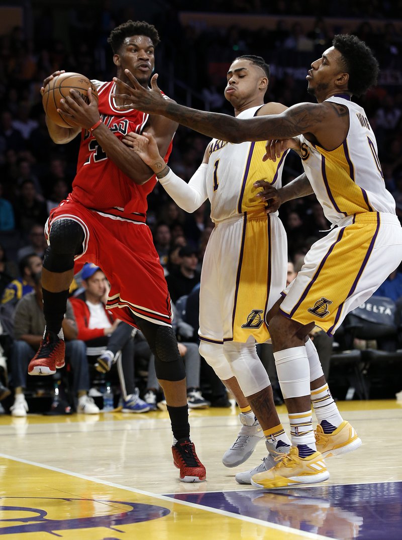 Chicago Bulls forward Jimmy Butler, left, leaps away from Los Angeles Lakers guard D'Angelo Russell, center, and guard Nick Young, right, to make a pass during the first half of an NBA basketball game in Los Angeles, Sunday, Nov. 20, 2016. (AP Photo/Alex Gallardo)