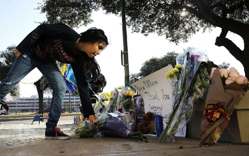 Faith Reyna leaves flowers Monday at a makeshift memorial for slain San Antonio police officer Benjamin Marconi.